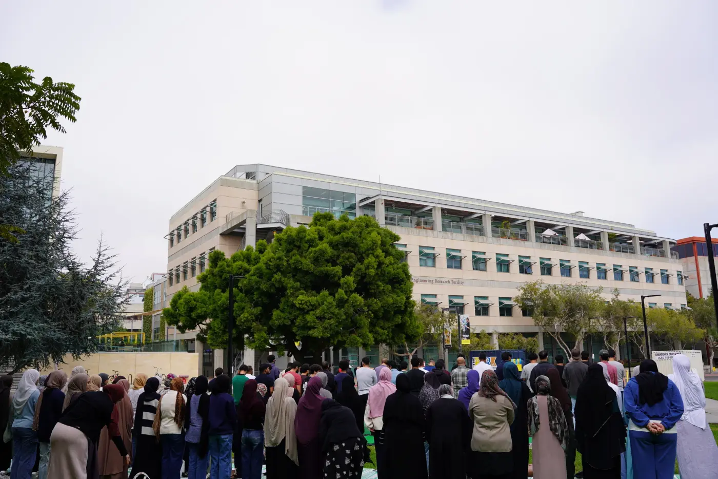 Attendees gathered on the lawn outside a campus building on an overcast day
